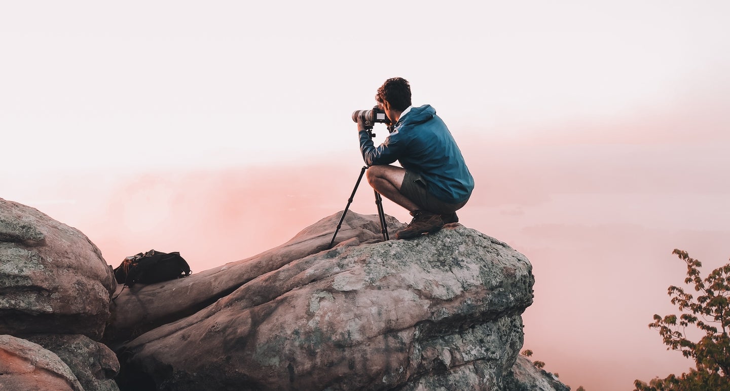 Person taking photo on high rock