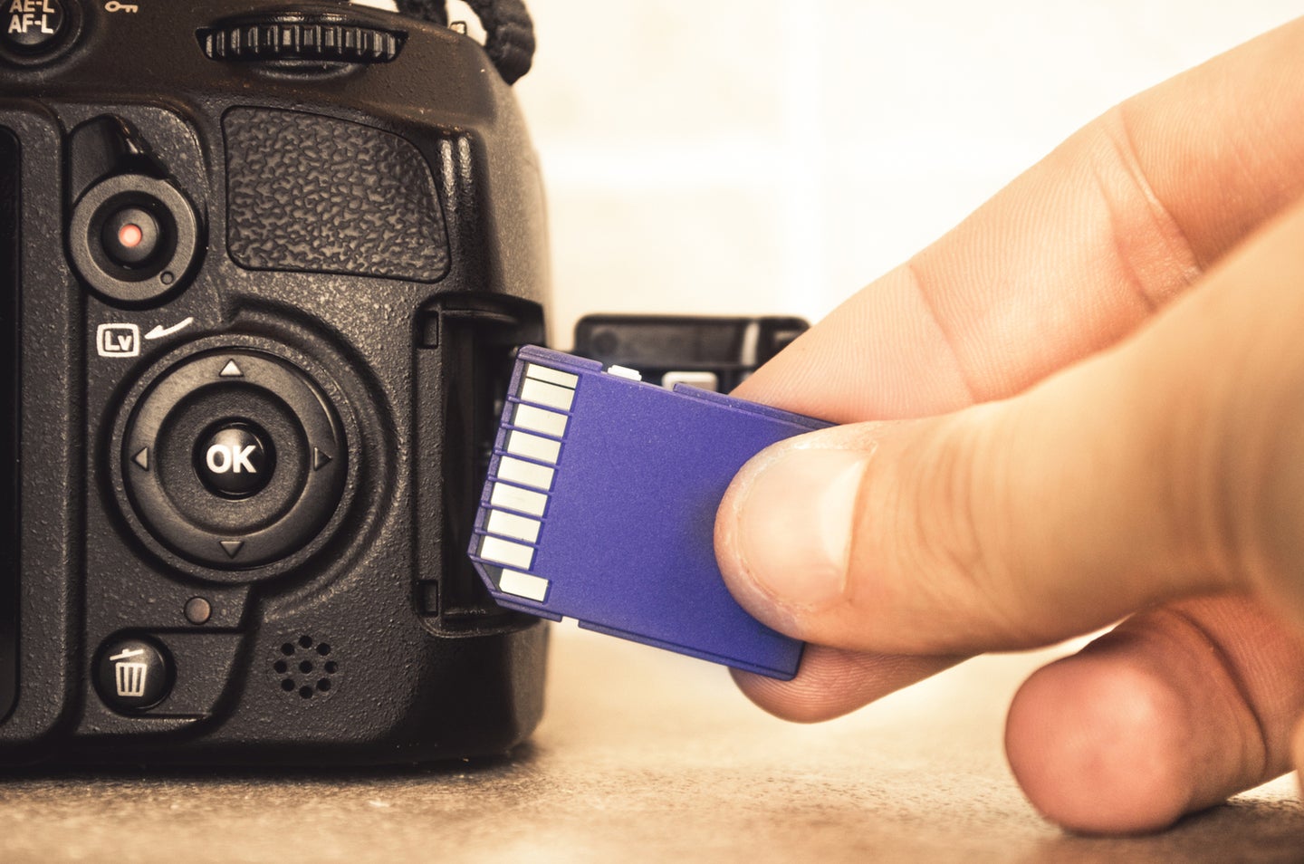 Hand inserting SD card into DSLR camera