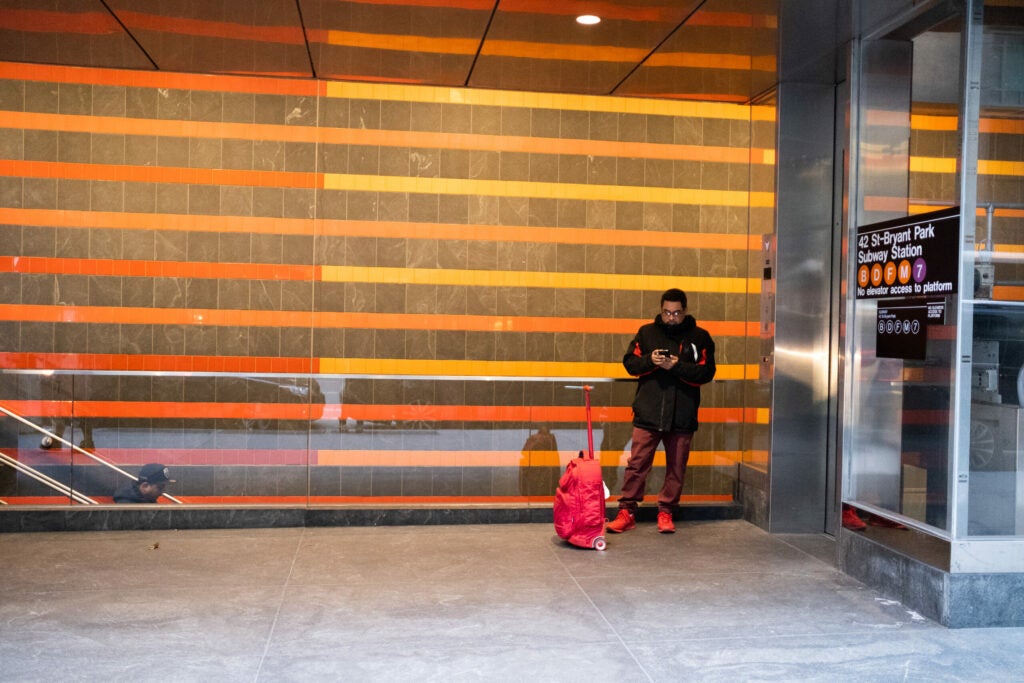 person with red luggage waiting at subway station