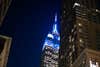 Empire state building lit up blue at night