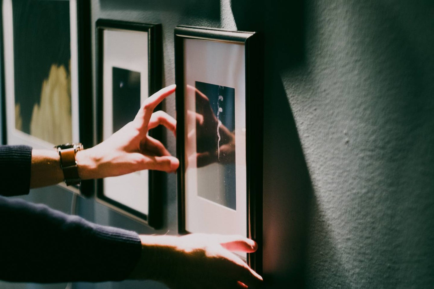 Hands aligning frame on the wall