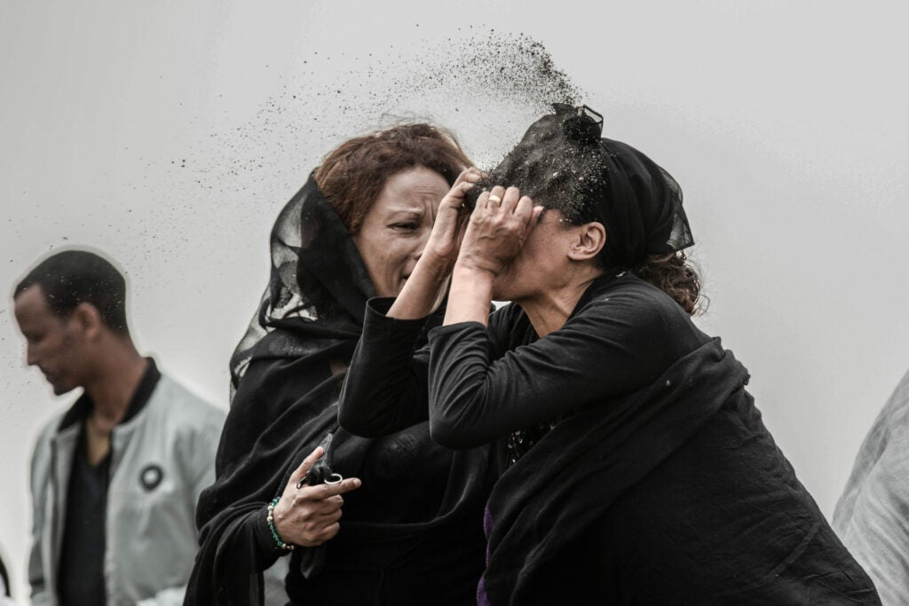 A relative of a victim of the crash of Ethiopian Airlines Flight ET302 throws dirt in her face as she grieves
