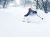 a person skiing in snow with a red hat on during the winter