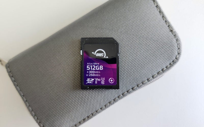 OWC Atlas Ultra SDXC 512GB memory card for cameras on a gray pouch resting on a white table