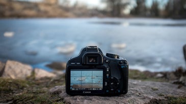 canon camera on a rock in front of a pond
