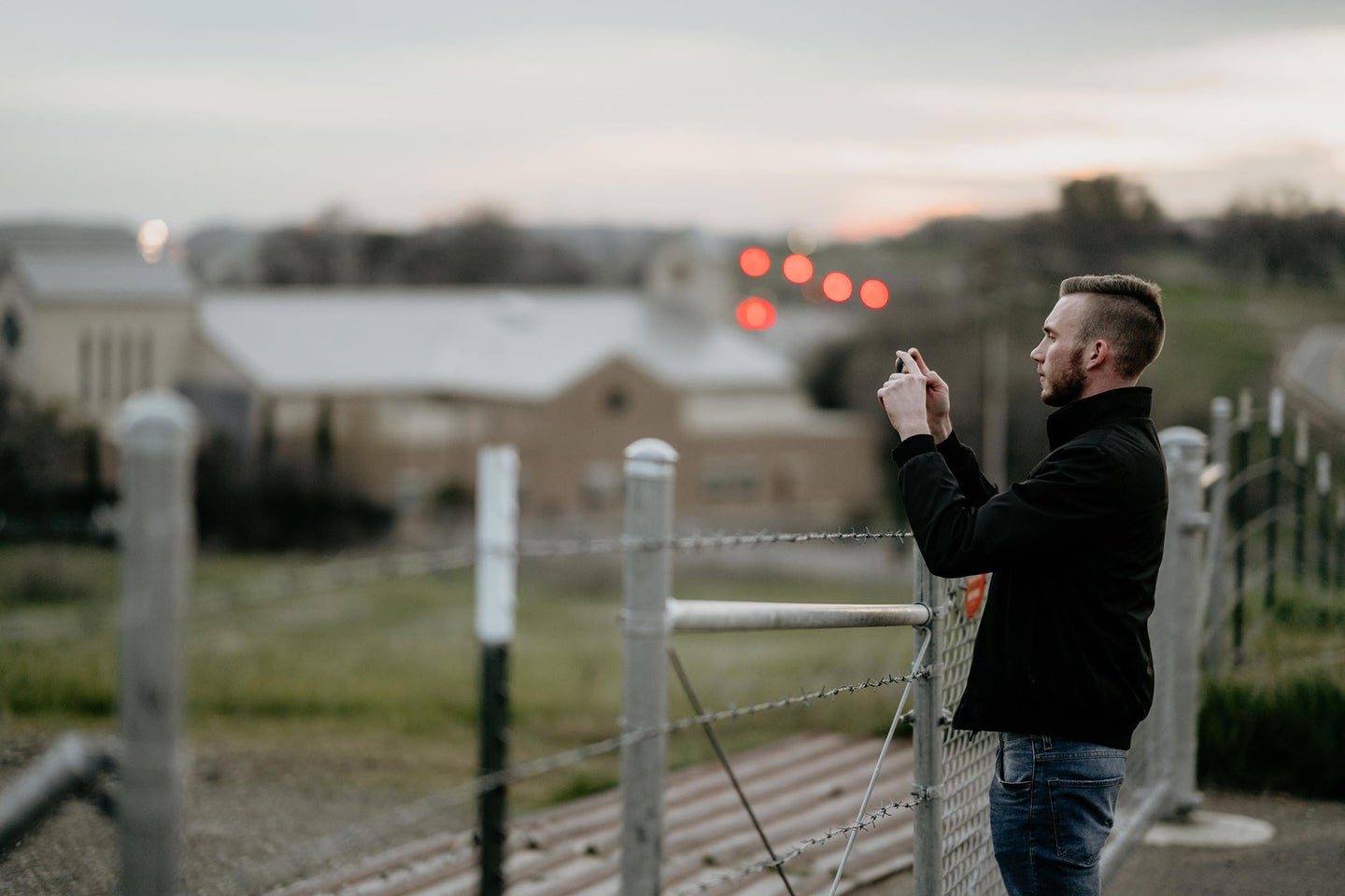 guy taking a photo with the best camera phone on a bridge.