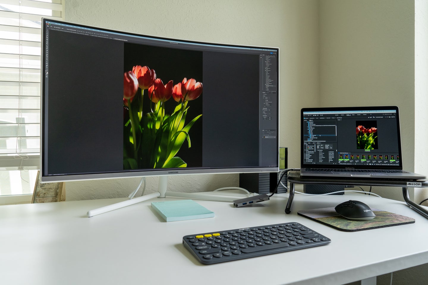 A desk with a monitor and laptop setup and Adobe Photoshop on the display.