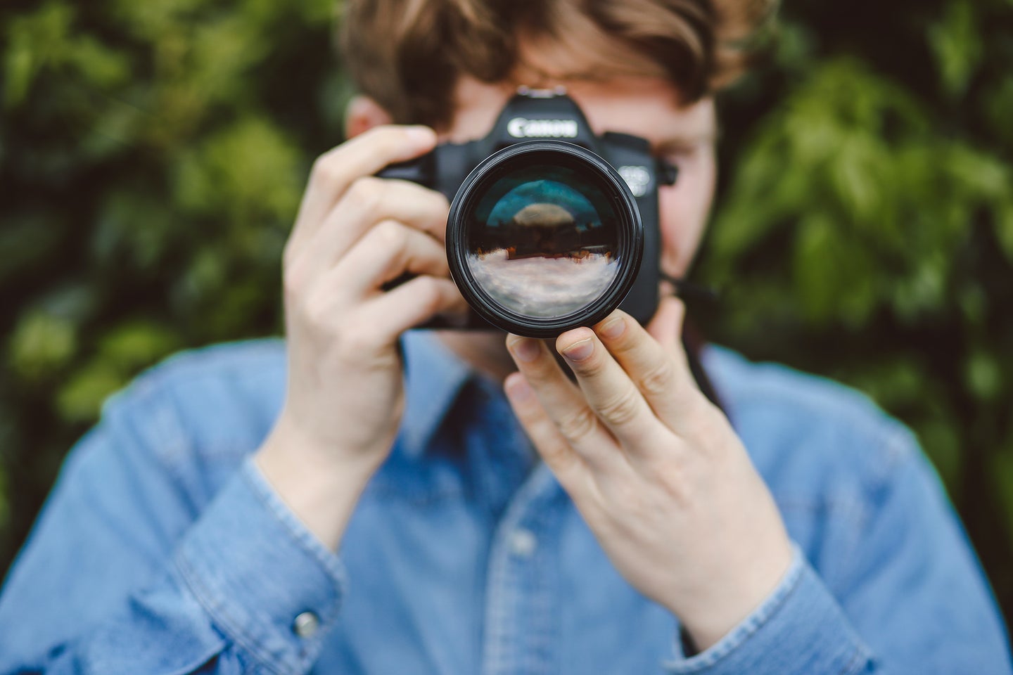 Person holding a the best DSLR camera for beginners in front of their face