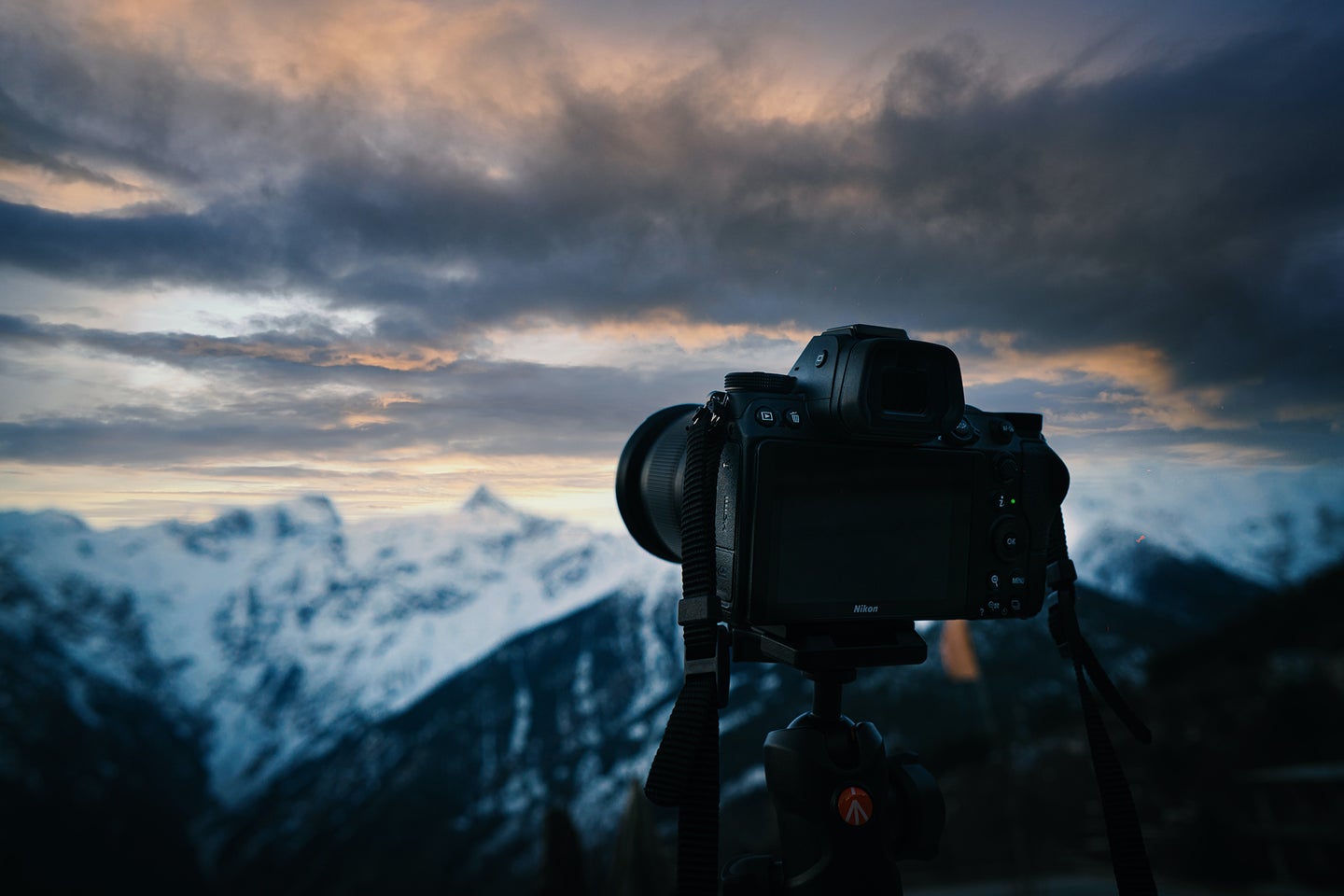 Best full frame camera on a tripod in front of a cloudy sky and snowy mountain