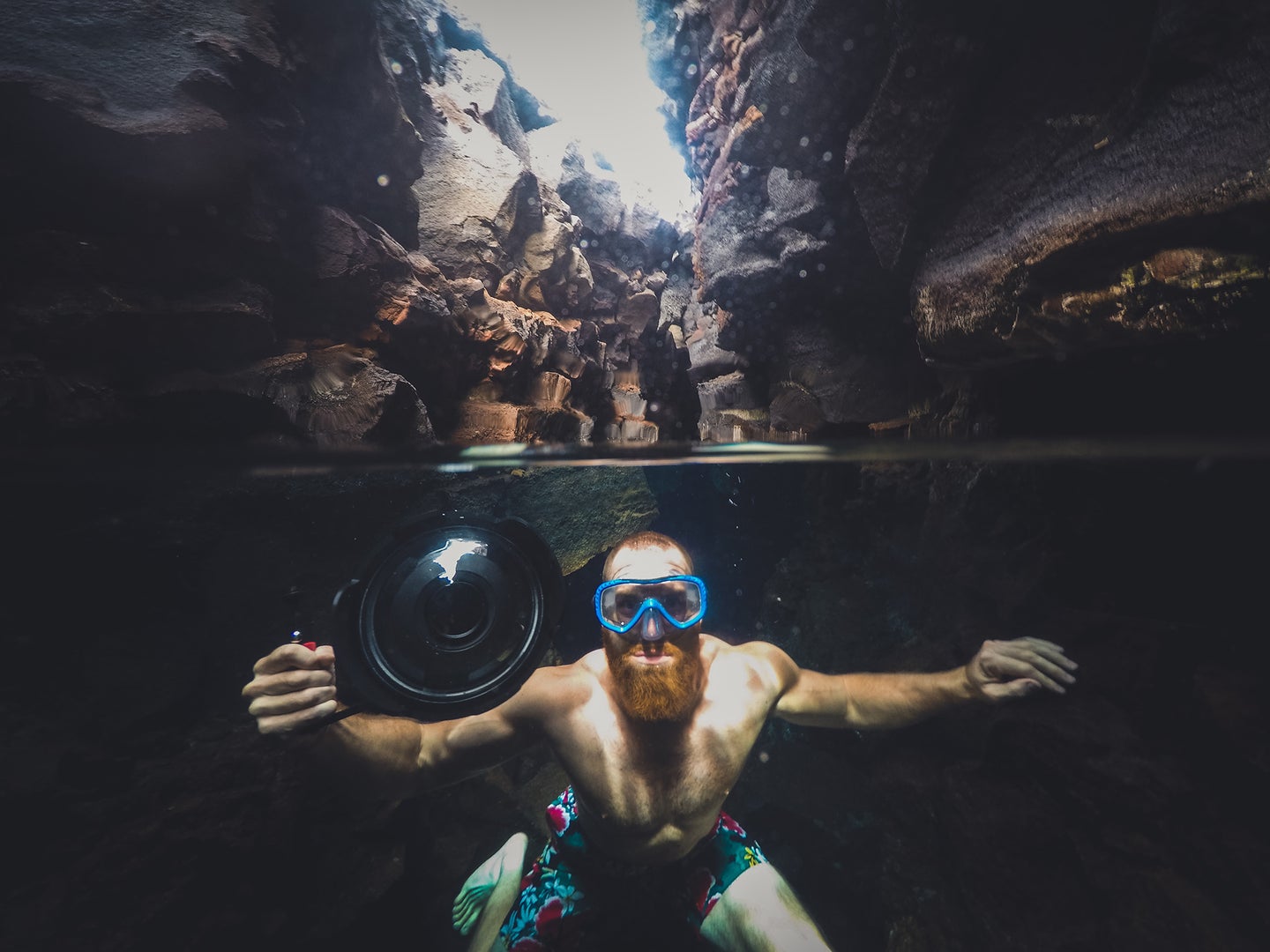 man with a beard underwater holding a camera with an underwater camera case