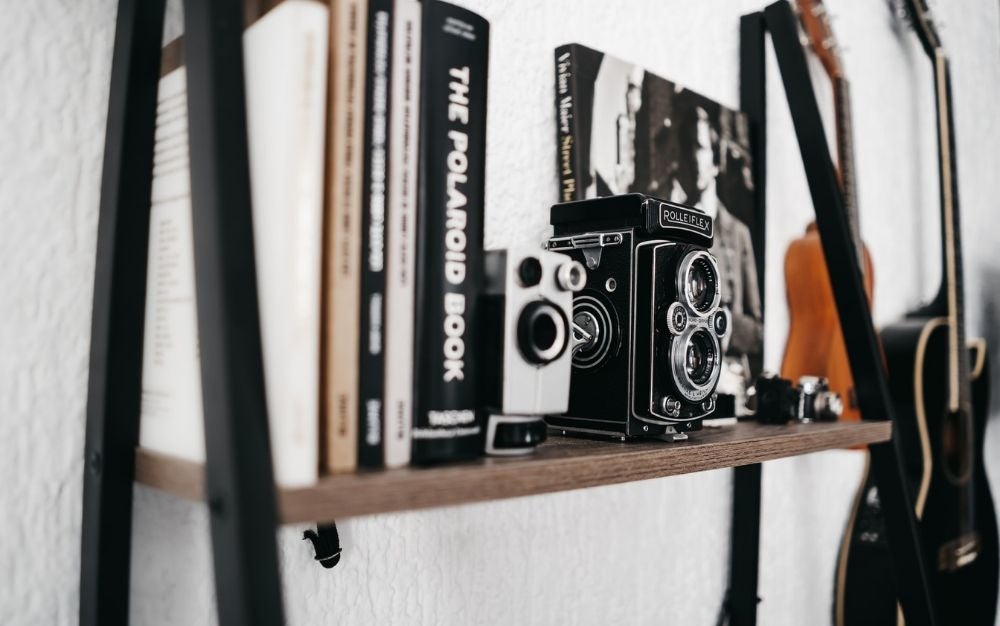 Two photographic cameras between the books lined up on the wall.