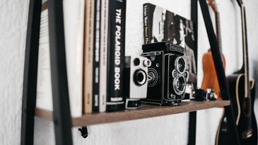 Two photographic cameras between the books lined up on the wall.