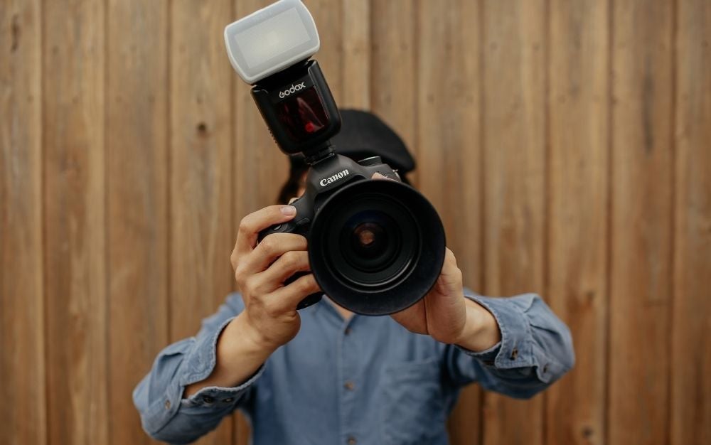 A man using Canon black professional camera in position to take photo.