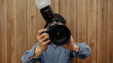 A man using Canon black professional camera in position to take photo.