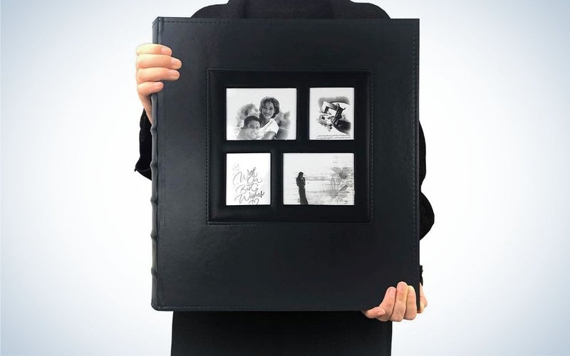 A man holding in his hands a big black photo album with four different photos on it.