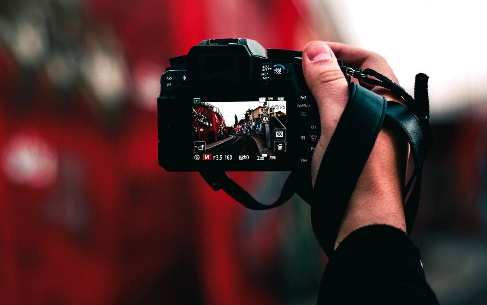 A black professional camera in a mans hand taking pictures.