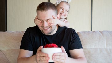 A little girl playing with her father closing her eyes with her hands.