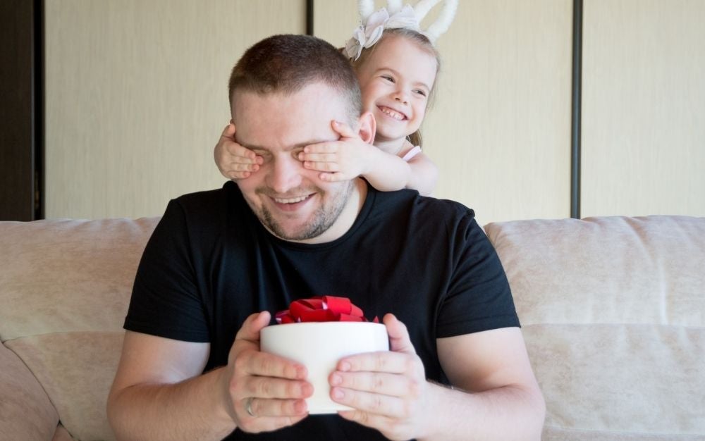 A little girl playing with her father closing her eyes with her hands.