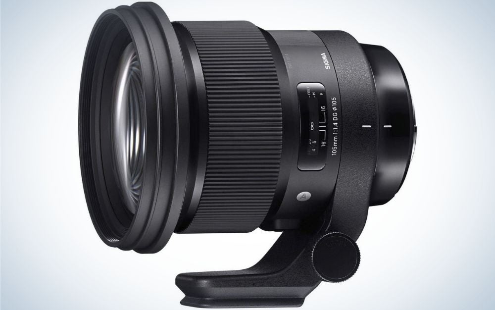 An all-black lens of a professional camera which looks sideways and with a light-colored glass front lens with a support to stand on.