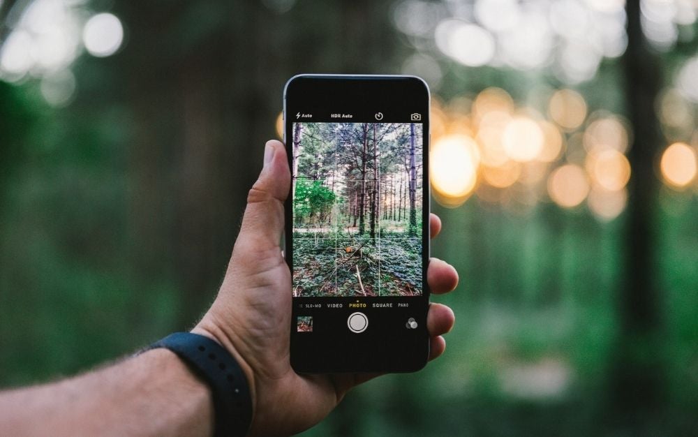 The hand of a man who has in his hand a phone with a color desktop and the picture is focused on the phone.