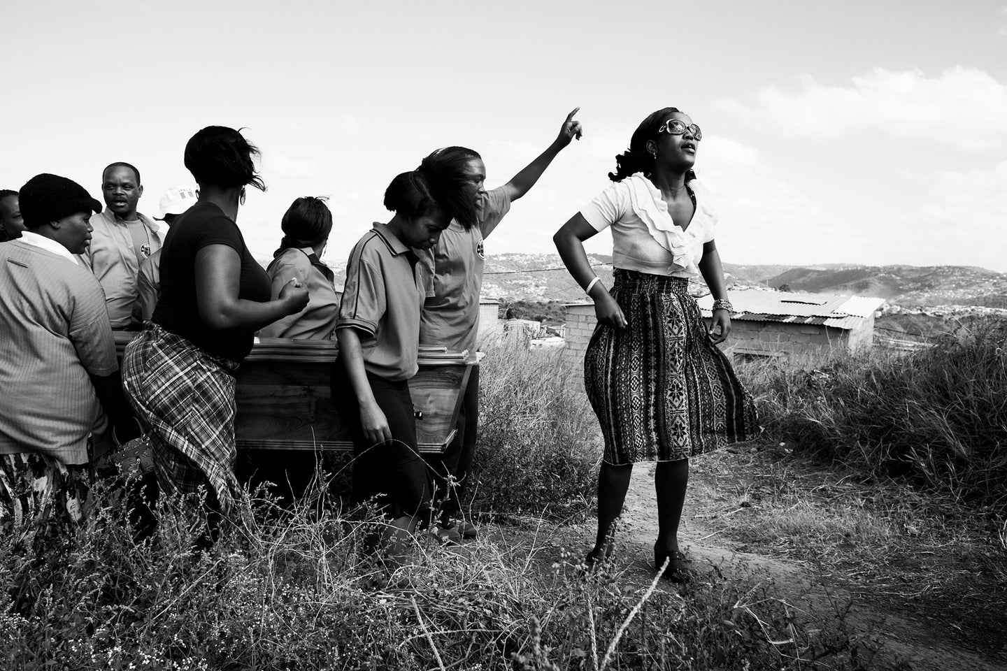 Thabsile Brightness Sishi, 25 (right), leads the funeral procession for her aunt Thembi Veze, along with her brother, Bongumenzi Knowledge Sishi, 15. Thabsile and Bongumenzi have been living with their aunt and her three children in the Richmond Farm Transit Camp near Durban, South Africa since 2009. ÒIn the camp, I canÕt say itÕs nice to stay hereÐ thereÕs no park, nowhere to play soccer, nowhere to rest,Ó says Bongumenzi. ÒItÕs too dangerous. ThereÕs no security. We are waiting for moving Ð they are still building the RDPs. They said we would be here two years.Ó