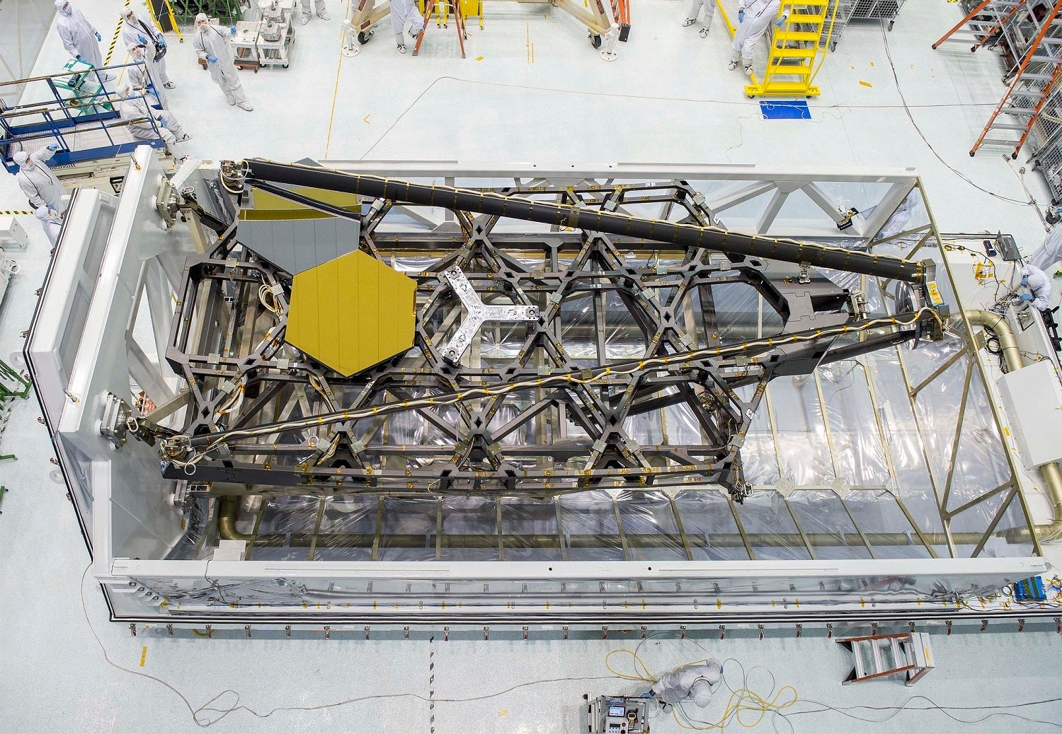 A bird’s-eye view of NASA Goddard’s cleanroom and the James Webb Space Telescope’s test backplane and mirrors sitting in their packing case.