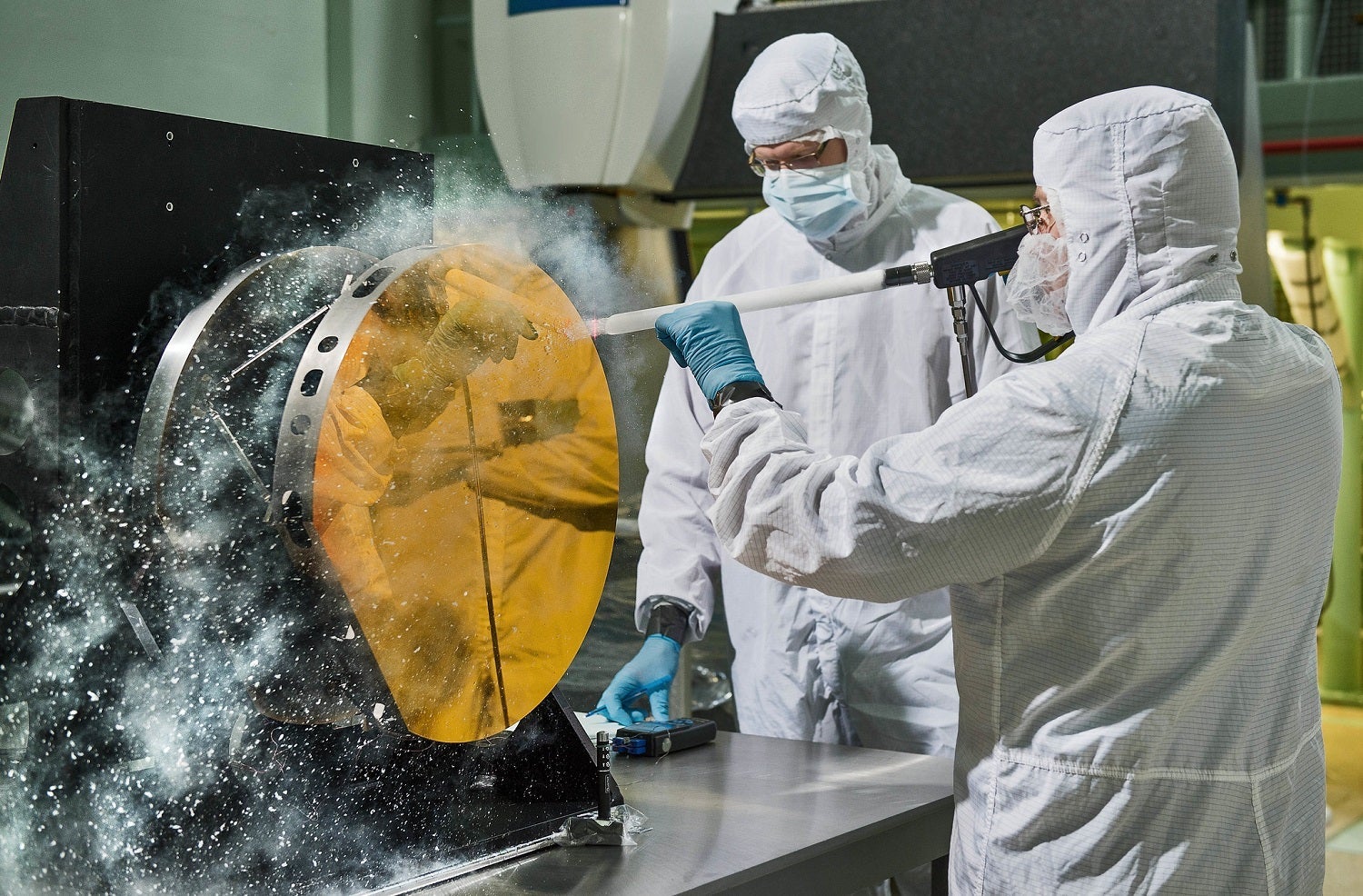 Just like drivers sometimes use snow to clean their car mirrors in winter, two Exelis Inc. engineers are practicing âsnow cleaning'â on a test telescope mirror.