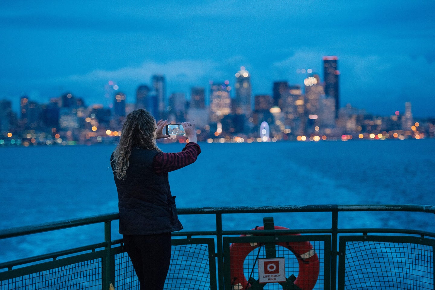 A women shooting a smartphone photo at dusk