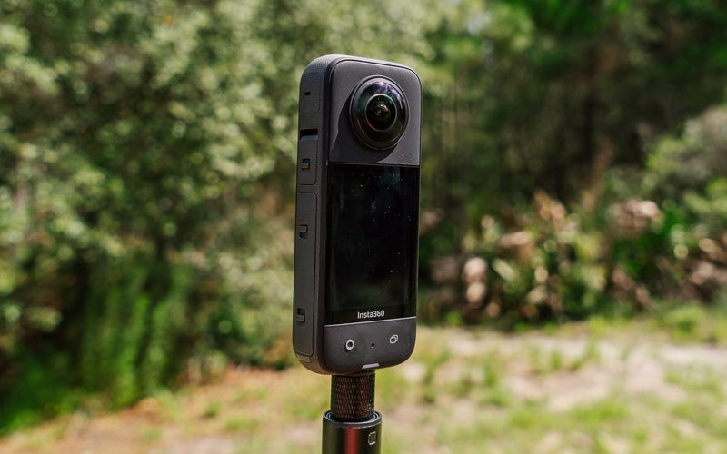 Insta360 X3 action camera with a forest in the background