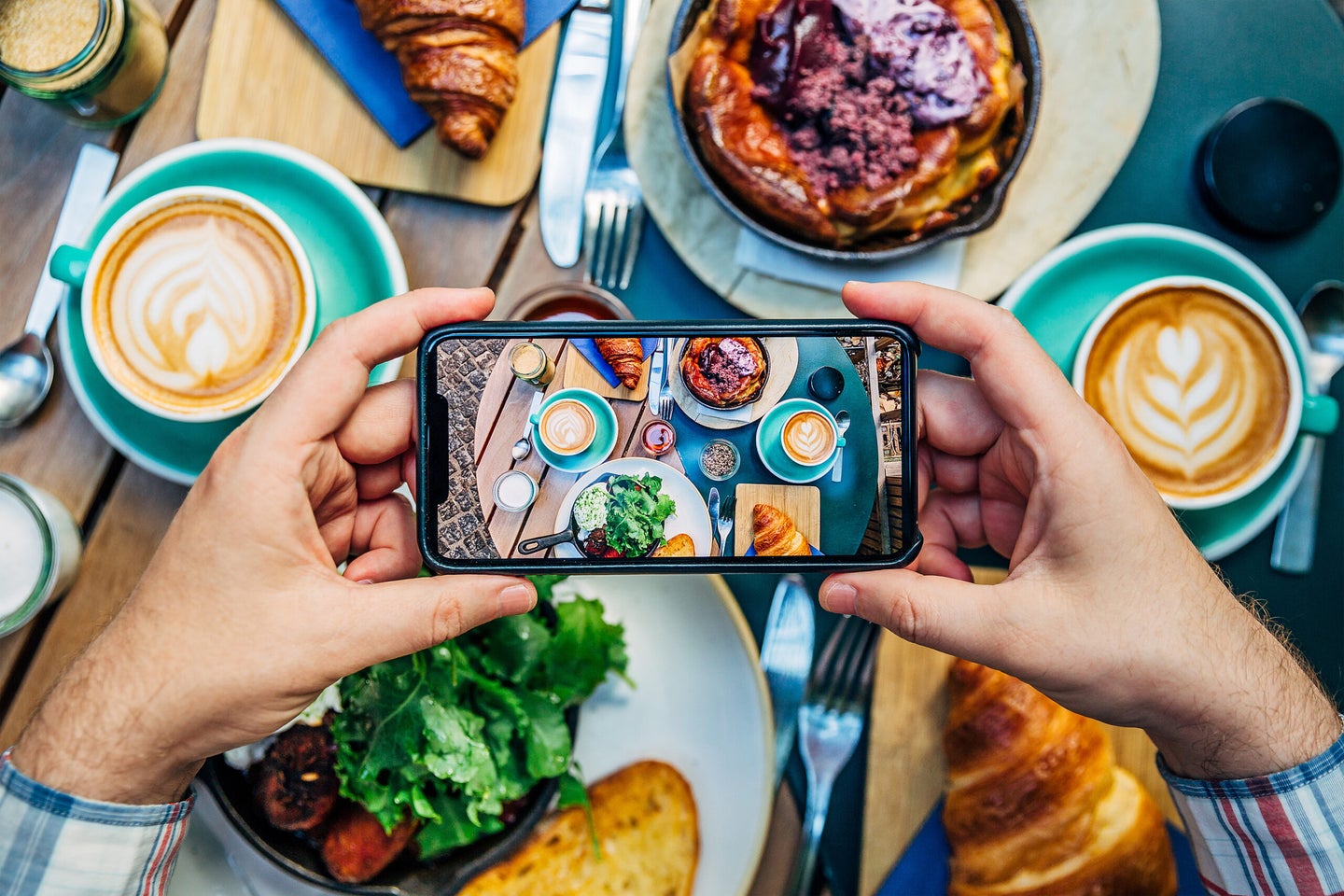 Man photographing breakfast in a cafe with smartphone