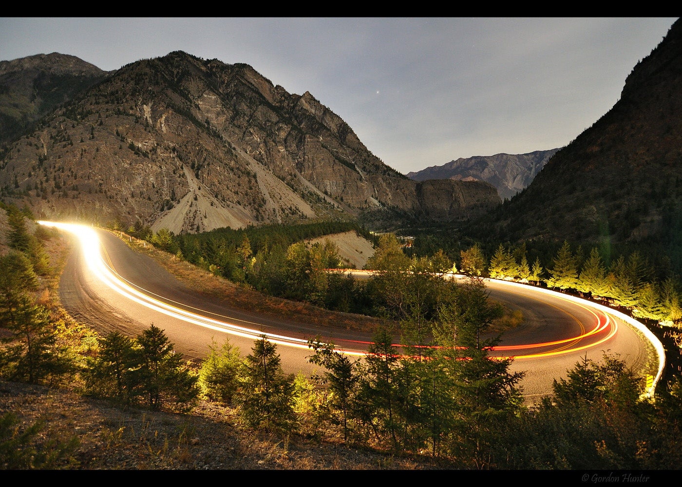 A long exposure shows a car going around a hairpin turn