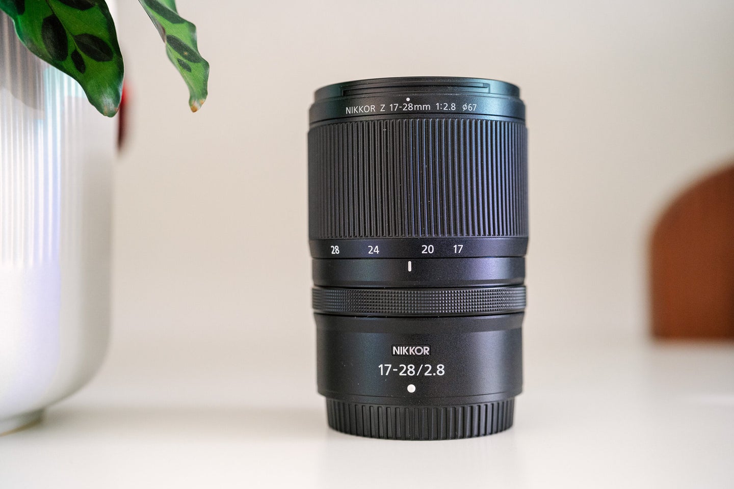 Nikon NIKKOR Z 17-28mm f/2.8 lens on a shelf with a potted plant