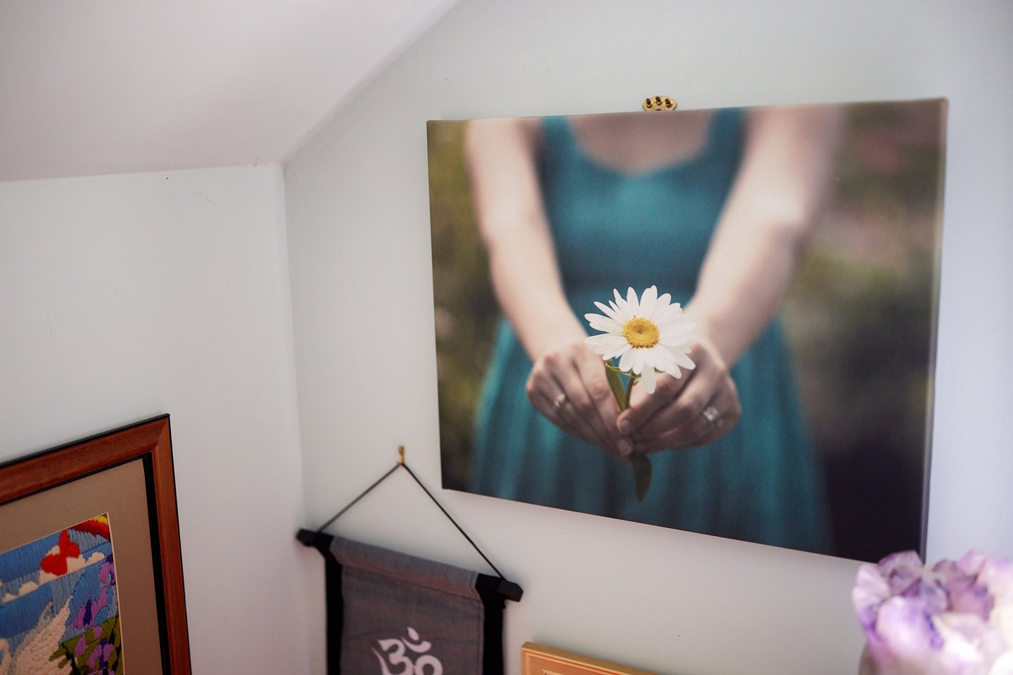 A canvas print of a woman holding a flower hanging on a wall.