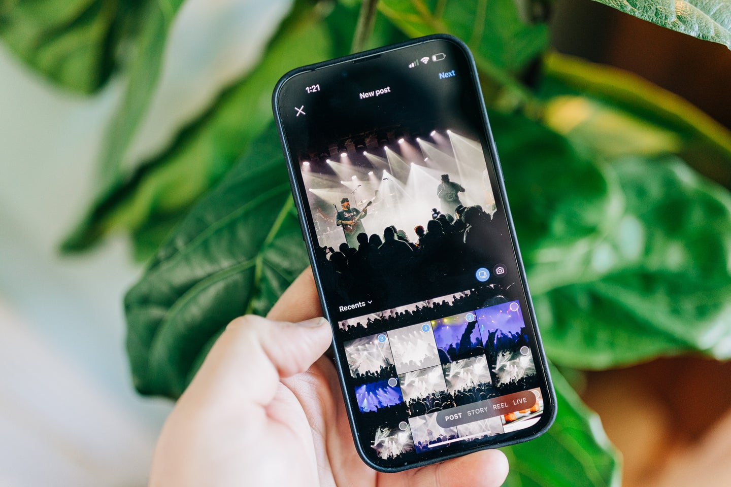 A hand holding a phone posting multiple photos on instagram