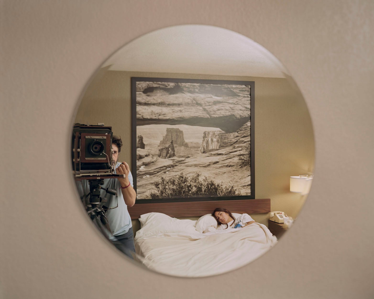 A film photograph of the photographer's reflection, captured in a circular mirror on the wall.
