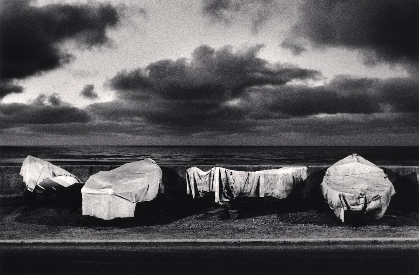 A black and white photo of draped boats along the seaside.