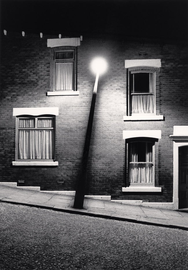 A black and white photo of a street lamp on a vacant street.