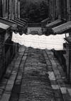 A black and white photo of laundry hanging on a line across an empty street.