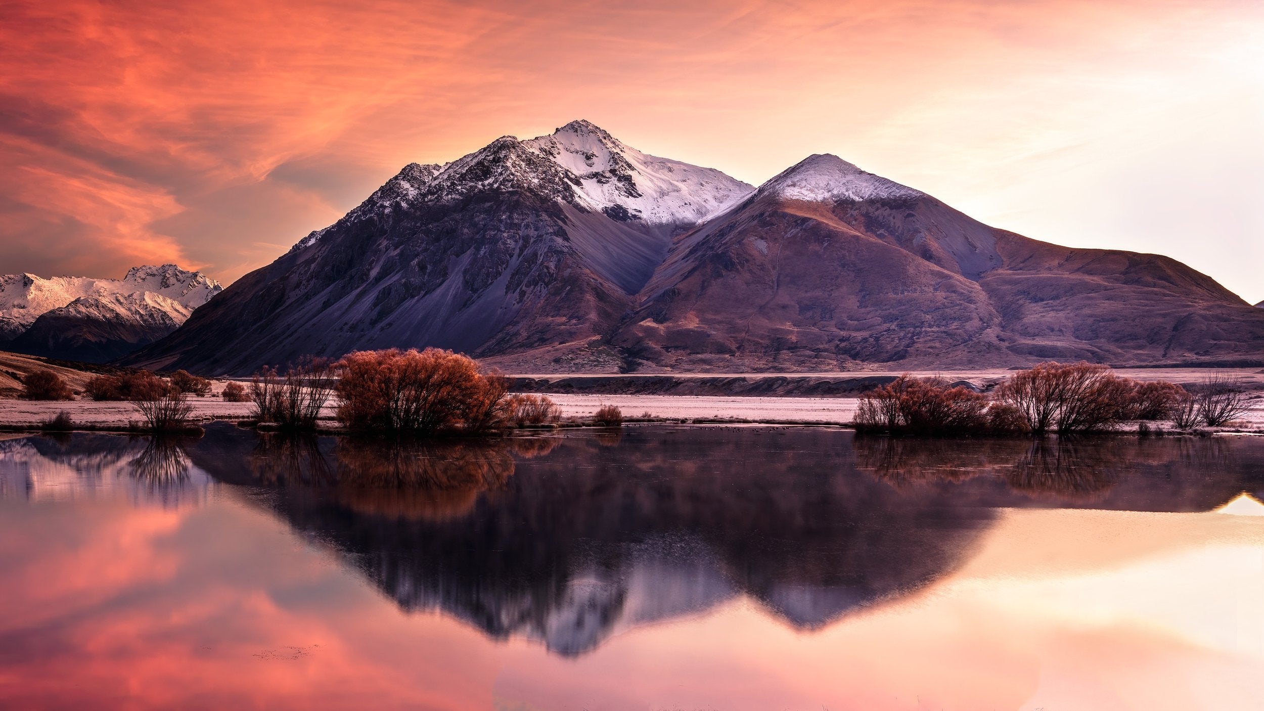 Mountains with an orange sunset and lake reflection.