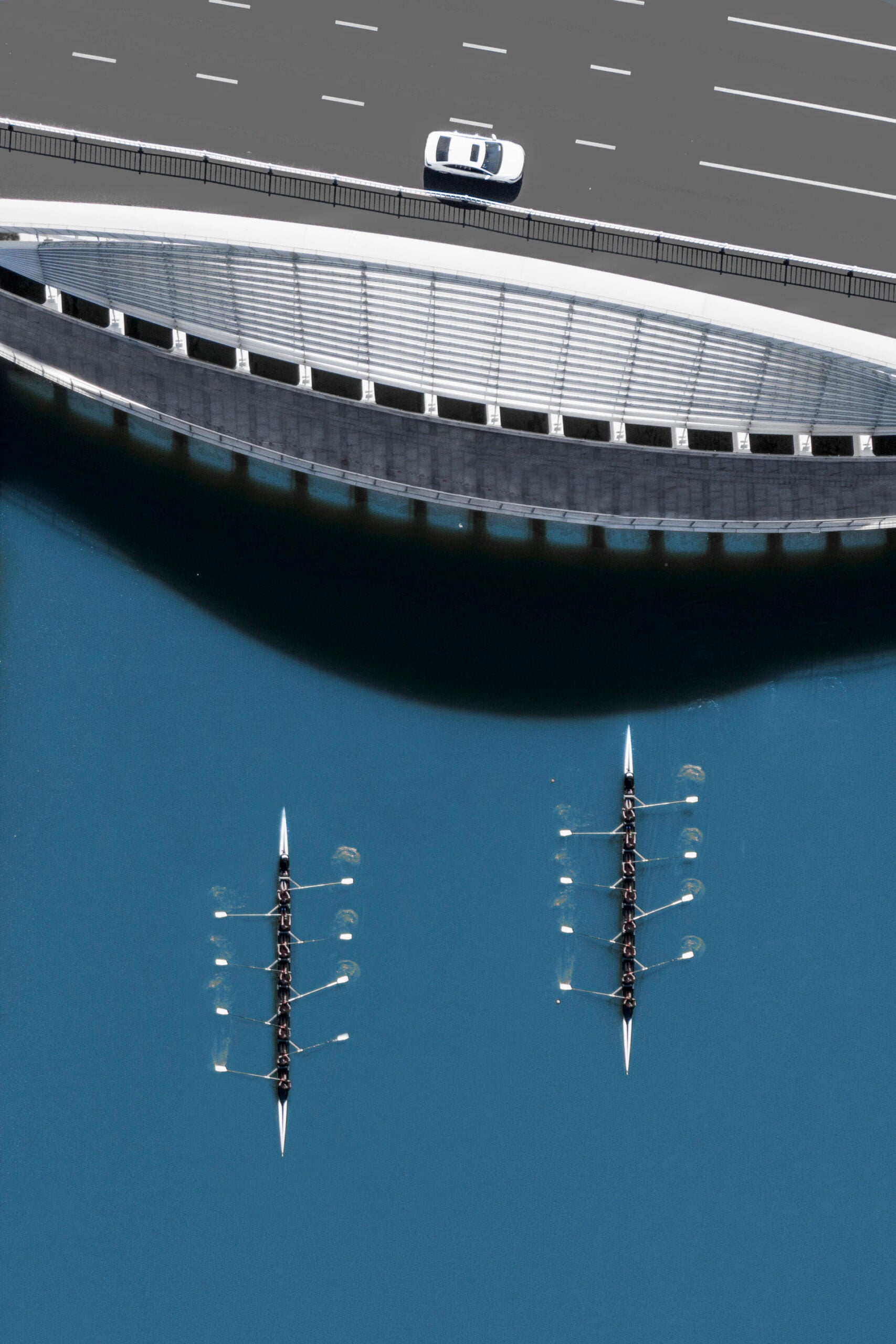 Two rowing boats racing towards a bridge.