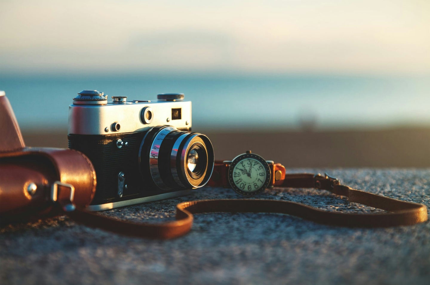 A film camera on a rock by the shore.
