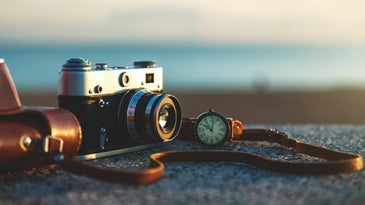A film camera on a rock by the shore.