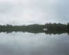 A misty lake with the roof of a house visible in the lake.