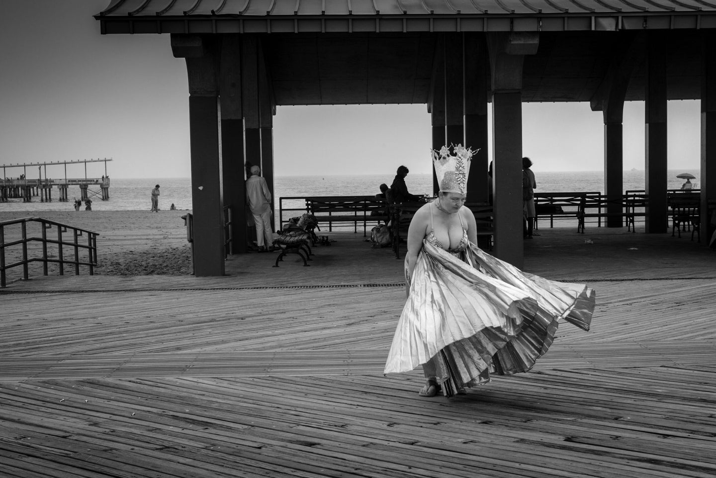 black and white photo of a woman's skirt flutters in the wind as she stands on a pier