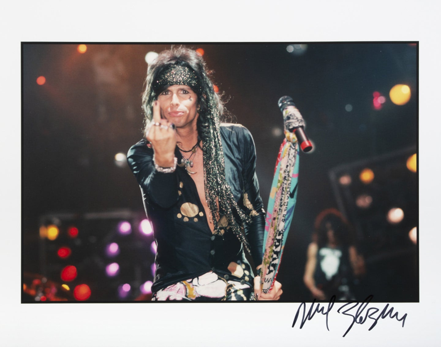 Steven Tyler of Aerosmith gives the finger as he poses with his microphone