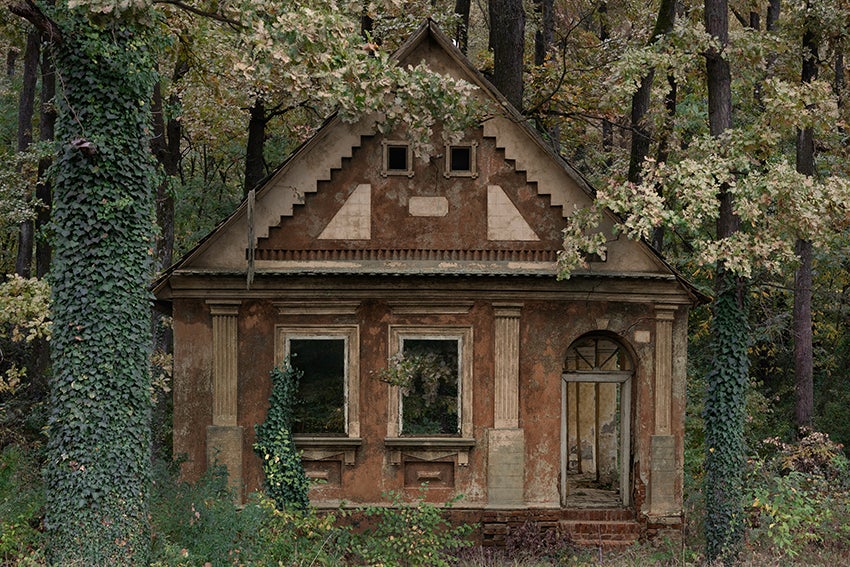 an old, abandoned house is overrun by vines and trees in a forest