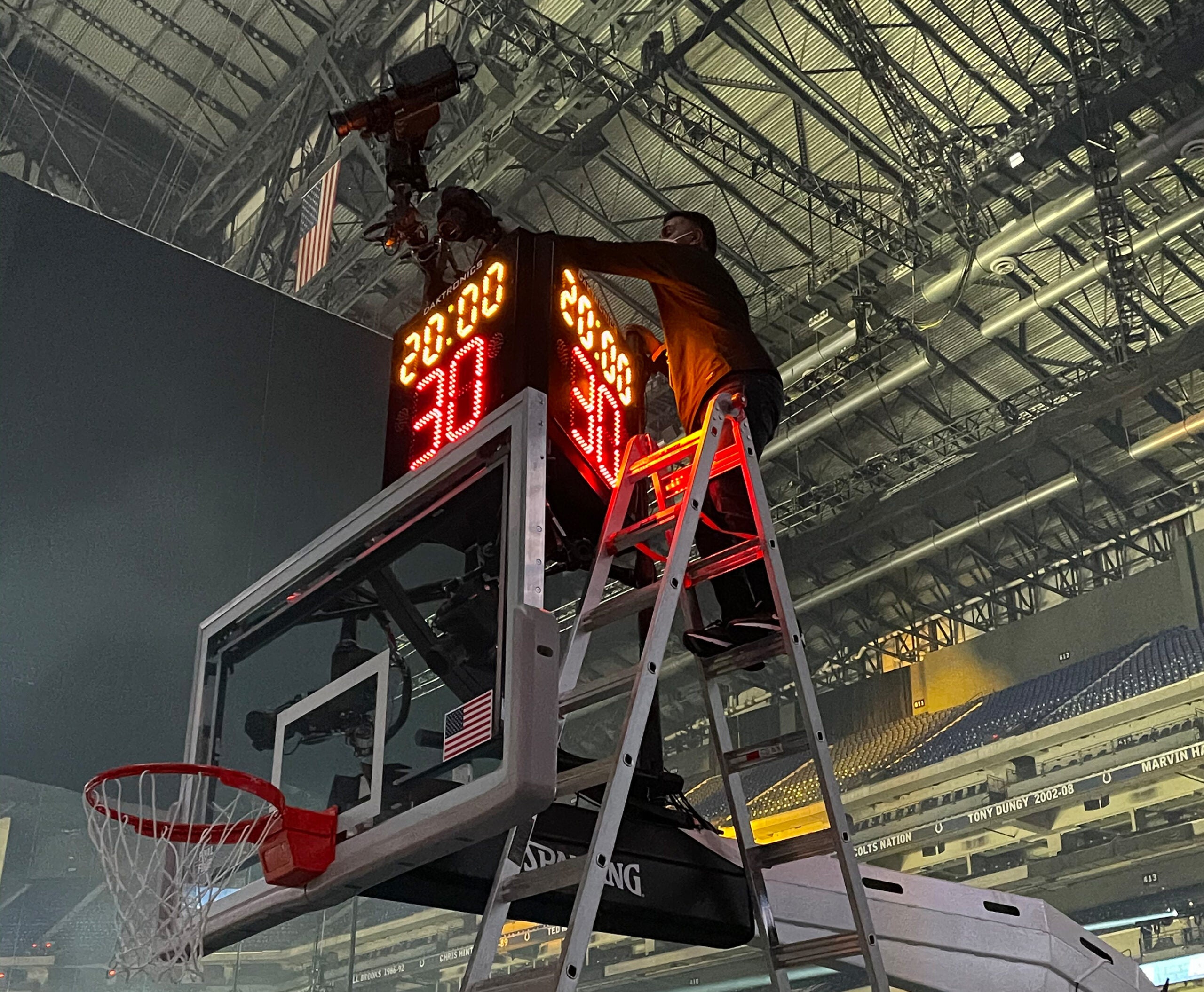 A technician checks an above the shot clock remote camera.