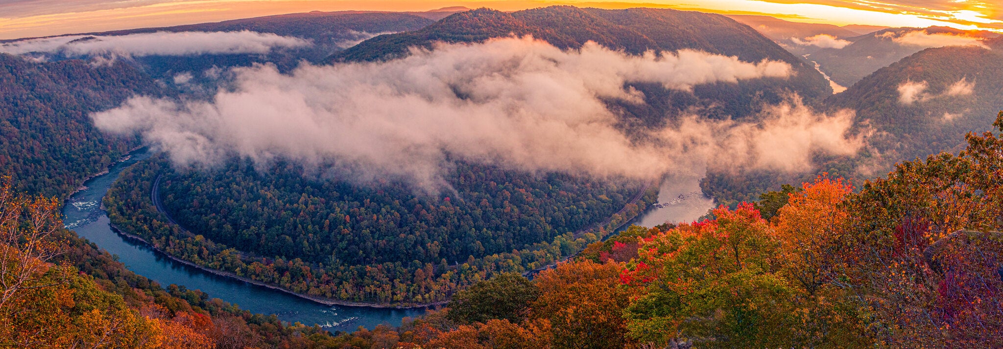 panorama of a valley at sunset. soft clouds blanket the trees