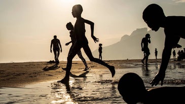 silhouette of children running towards the water on the beach