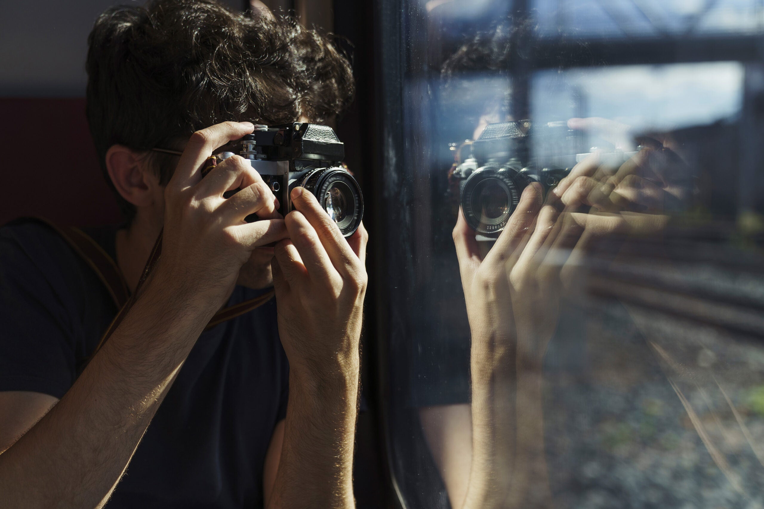 Man traveling by train taking picture with old-fashioned camera